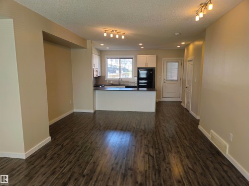 Wood-finish flooring throughout, track lighting, recessed lighting, white kitchen cabinetry, and dark countertops - #69 903 Crystallina Nera Wy Nw, Edmonton, AB 