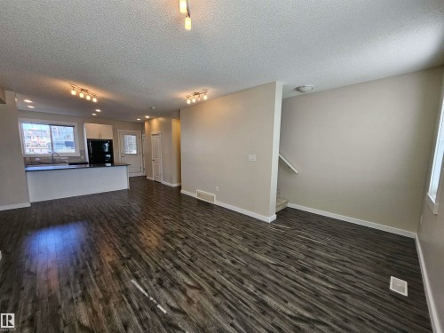 Open-concept living area with dark wood-finish flooring, recessed lighting, and track lighting - #69 903 Crystallina Nera Wy Nw, Edmonton, AB 