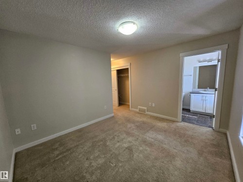 Neutral wall color, carpeted flooring, overhead lighting, closet with bi-fold door, and bathroom entry with vanity - #69 903 Crystallina Nera Wy Nw, Edmonton, AB 