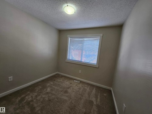 Carpeted room with a window featuring blinds, a ceiling-mounted light fixture, and neutral wall tones - #69 903 Crystallina Nera Wy Nw, Edmonton, AB 