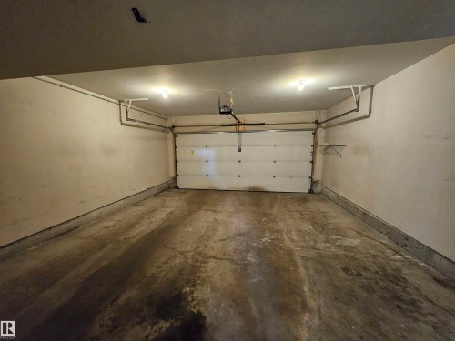 Enclosed garage featuring a concrete floor, overhead lighting, and built-in shelving - #69 903 Crystallina Nera Wy Nw, Edmonton, AB 