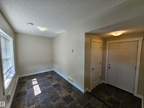 Entry area featuring a paneled door, flush-mount lighting, and textured ceiling - #69 903 Crystallina Nera Wy Nw, Edmonton, AB 