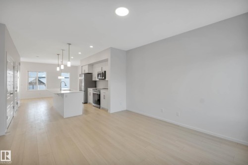 Open-concept living space featuring wood-finish flooring, recessed lighting, and a kitchen island with pendant lighting - 5239 - 5245 21A Avenue Sw, Edmonton, AB 