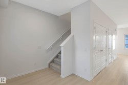 Carpeted staircase with a white handrail, light wood-finish flooring, and white paneled doors - 