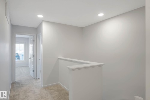 Recessed ceiling lighting, light gray wall finishes, neutral carpet flooring, white trim details, and a white half-wall railing - 5239 - 5245 21A Avenue Sw, Edmonton, AB 