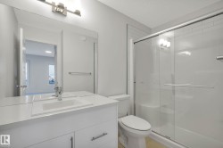 White vanity with integrated sink, glass-enclosed shower with sliding door, and horizontal tile detailing - 