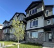 Three-story townhome with a mixed material exterior, featuring stone veneer and horizontal siding - 5239 - 5245 21A Avenue Sw, Edmonton, AB 
