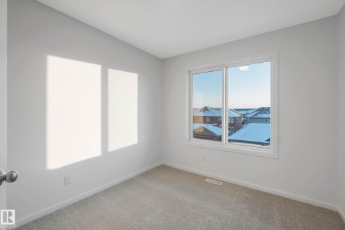 Neutral wall paint with soft gray carpeting, featuring a large window with white trim - 5239 - 5245 21A Avenue Sw, Edmonton, AB 