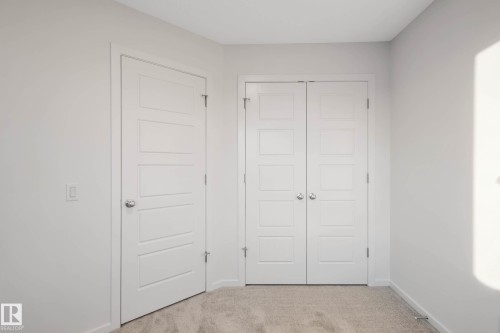 White interior doors with panel detailing, coordinating bi-fold closet doors, and light-colored carpeting - 5239 - 5245 21A Avenue Sw, Edmonton, AB 