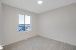 Recessed ceiling lighting, light gray wall paint, gray carpet flooring, white trim, and a white-framed window - 