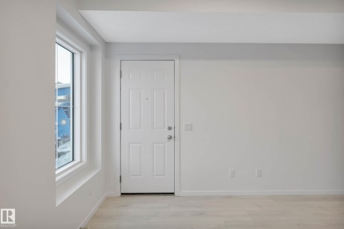 Wood-finish flooring with a white paneled door and large window - 5239 - 5245 21A Avenue Sw, Edmonton, AB 