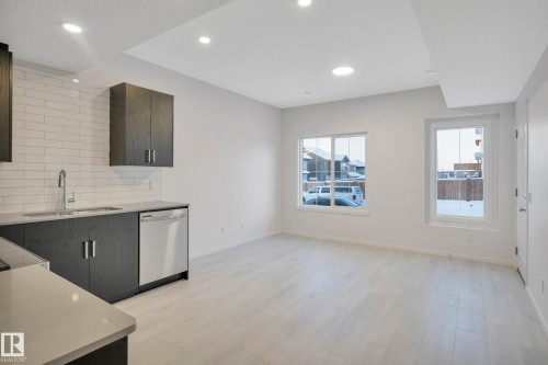 Kitchenette with dark wood-finish cabinetry, stainless steel dishwasher, and white subway tile backsplash - 5239 - 5245 21A Avenue Sw, Edmonton, AB 