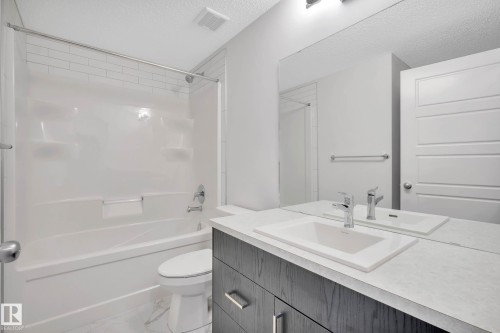 White subway tile shower surround, integrated bathtub, vanity with undermount sink, chrome faucet, and full-width mirror - 5239 - 5245 21A Avenue Sw, Edmonton, AB 