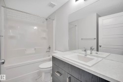 White subway tile shower surround, integrated bathtub, vanity with undermount sink, chrome faucet, and full-width mirror - 
