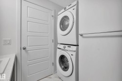 White stackable washer and dryer, white paneled door, light-colored countertop, and light-colored flooring - 