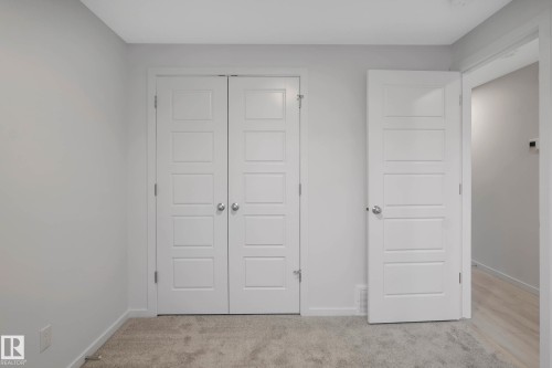 Neutral wall color, carpeted flooring, two panel doors with modern hardware, and a single hinged door - 5239 - 5245 21A Avenue Sw, Edmonton, AB 