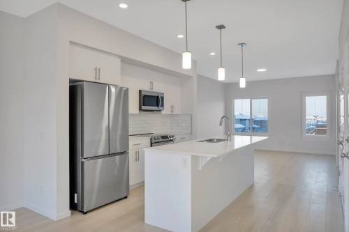 Kitchen with a stainless steel French door refrigerator, white shaker-style cabinetry, and a white subway tile backsplash - 5239 - 5245 21A Avenue Sw, Edmonton, AB 
