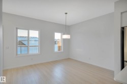 Light wood-finish flooring, two large windows, and a modern pendant light fixture - 