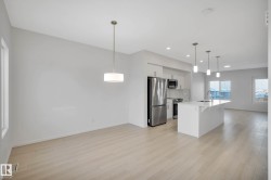 Open concept design with wood-finish flooring, white walls, and abundant natural light - 