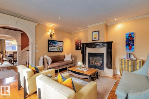 Living area with arched walkways, crown molding, light wood-style floors, a premium fireplace, and recessed lighting - 6306 111 Avenue Nw, Edmonton, AB 