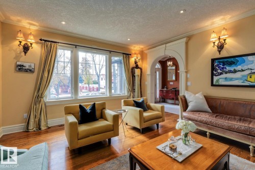 Living room with arched walkways, crown molding, wood finished floors, and a textured ceiling - 6306 111 Avenue Nw, Edmonton, AB 