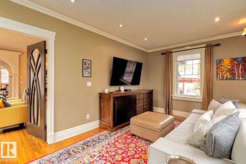 Living area with light wood-style flooring, crown molding, recessed lighting, arched walkways, and decorative columns - 6306 111 Avenue Nw, Edmonton, AB 