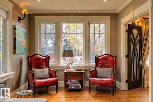 Sitting room featuring ornamental molding, wood finished floors, and a textured ceiling - 6306 111 Avenue Nw, Edmonton, AB 