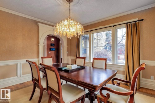 Dining space featuring arched walkways, a chandelier, light wood-style floors, a wainscoted wall, and ornamental molding - 6306 111 Avenue Nw, Edmonton, AB 
