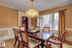 Dining space featuring arched walkways, a chandelier, light wood-style floors, a wainscoted wall, and ornamental molding - 