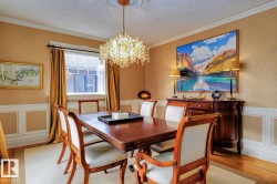 Dining area featuring a decorative wall, wainscoting, light wood-style flooring, a chandelier, and ornamental molding - 