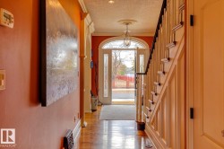 Entrance foyer featuring crown molding, a textured ceiling, wood finished floors, and stairs - 