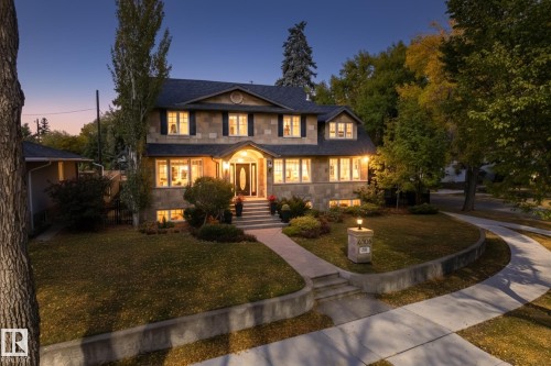 View of front of house featuring a lawn, roof with shingles, and stone siding - 6306 111 Avenue Nw, Edmonton, AB 