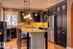 Kitchen with tasteful backsplash, appliances with stainless steel finishes, light stone countertops, pendant lighting, and glass insert cabinets - 