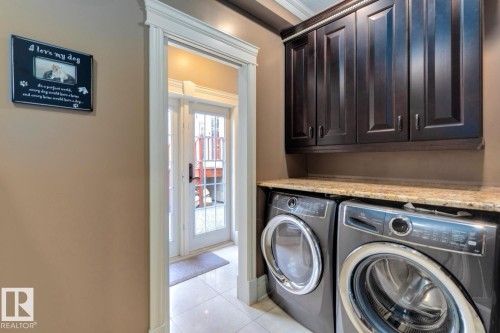 Laundry area featuring cabinet space, washer and clothes dryer, and light tile patterned floors - 6306 111 Avenue Nw, Edmonton, AB 