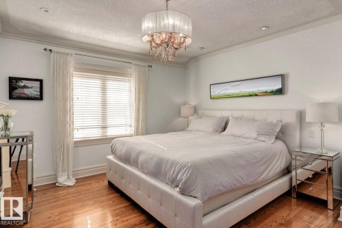 Bedroom featuring a textured ceiling, wood finished floors, ornamental molding, and a chandelier - 6306 111 Avenue Nw, Edmonton, AB 