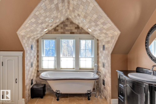 Full bathroom with a soaking tub, vanity, healthy amount of natural light, vaulted ceiling, and tile patterned floors - 6306 111 Avenue Nw, Edmonton, AB 