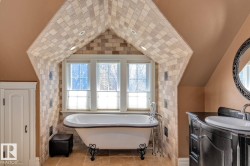 Full bathroom with a soaking tub, vanity, healthy amount of natural light, vaulted ceiling, and tile patterned floors - 