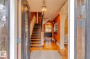 Foyer entrance with a chandelier, arched walkways, light wood finished floors, stairs, and ornamental molding - 6306 111 Avenue Nw, Edmonton, AB 