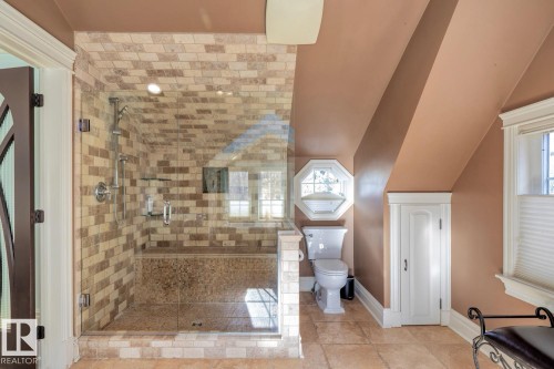Full bath with lofted ceiling, a shower stall, healthy amount of natural light, and tile patterned flooring - 6306 111 Avenue Nw, Edmonton, AB 