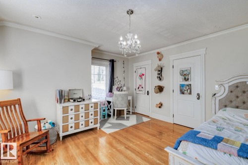 Bedroom with crown molding, light wood-type flooring, and a chandelier - 6306 111 Avenue Nw, Edmonton, AB 