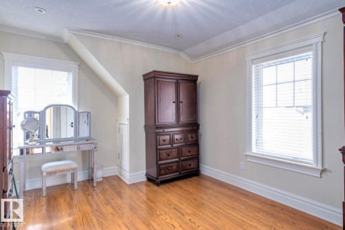 Bedroom featuring ornamental molding, light wood-style flooring, and a textured ceiling - 6306 111 Avenue Nw, Edmonton, AB 