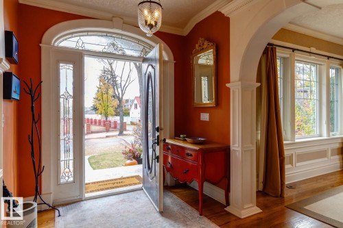 Entrance foyer featuring light wood-style flooring, crown molding, arched walkways, plenty of natural light, and a chandelier - 6306 111 Avenue Nw, Edmonton, AB 