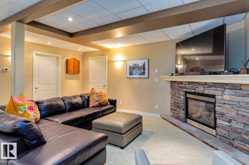 Living room featuring a fireplace, a drop ceiling, light colored carpet, and recessed lighting - 6306 111 Avenue Nw, Edmonton, AB 