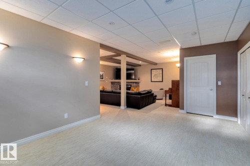 Living area with a stone fireplace, a paneled ceiling, and light colored carpet - 6306 111 Avenue Nw, Edmonton, AB 