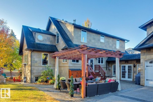 Rear view of house with a patio area, outdoor lounge area, a pergola, and stone siding - 6306 111 Avenue Nw, Edmonton, AB 