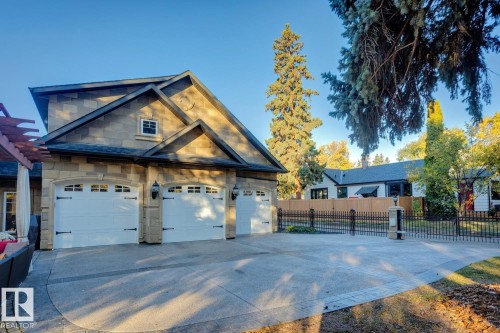 View of property exterior featuring a garage, concrete driveway, and stone siding - 6306 111 Avenue Nw, Edmonton, AB 