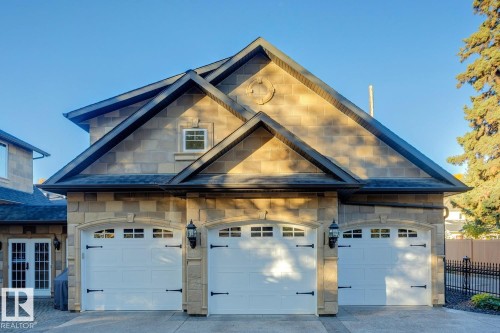 View of front of property featuring stone siding, a garage, concrete driveway, french doors, and a shingled roof - 6306 111 Avenue Nw, Edmonton, AB 