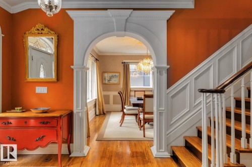 Entrance foyer featuring a chandelier, arched walkways, ornamental molding, light wood-style flooring, and a wainscoted wall - 6306 111 Avenue Nw, Edmonton, AB 