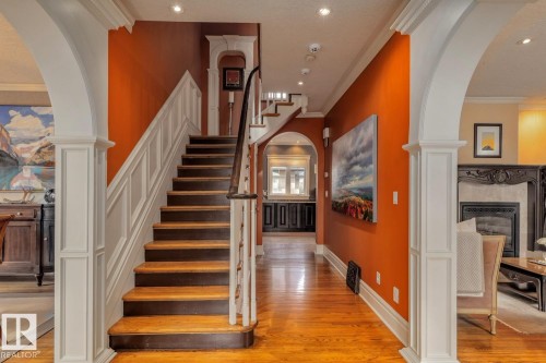 Staircase with arched walkways, ornamental molding, wood finished floors, a premium fireplace, and recessed lighting - 6306 111 Avenue Nw, Edmonton, AB 