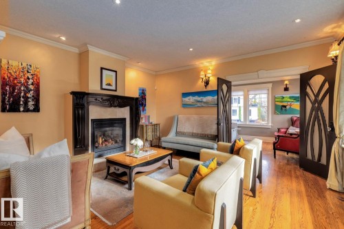 Living room featuring ornamental molding, a high end fireplace, wood finished floors, and recessed lighting - 6306 111 Avenue Nw, Edmonton, AB 